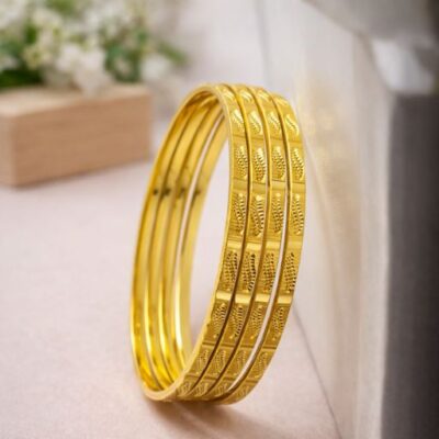 Exude a sense of organic elegance with this set of four gold-toned bangles. Featuring a beautiful interplay of polished surfaces and intricate botanical engraving, these bangles are a masterclass in textural design, offering a timeless look inspired by nature.