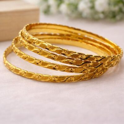 Celebrate the artistry of traditional gold-work with this set of four gold-toned bangles. Featuring a rhythmic interplay of fluid swirls and textured engraving, these bangles offer a rich, multi-dimensional look that captures the essence of classic elegance.