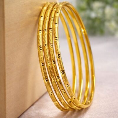 Elevate your jewelry collection with a sophisticated blend of organic inspiration and modern precision. This set of four gold-toned bangles features a rhythmic, bamboo-inspired silhouette, offering a masterclass in textural contrast and timeless elegance.