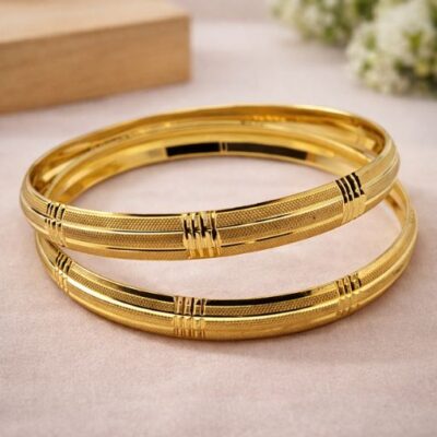 Exude a masterclass in gold craftsmanship with this pair of stunning gold-toned bangles. Featuring a sophisticated interplay of textures and structured lines, these bangles offer a bold yet refined look that anchors any jewelry ensemble with timeless elegance.
