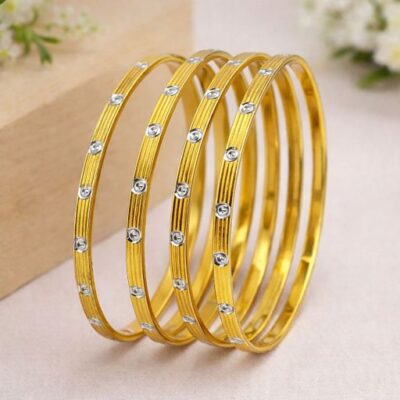 Elevate your signature style with a masterclass in linear elegance. This set of four gold-toned bangles features a sophisticated architectural design, blending rhythmic ribbing with radiant accents for a look that is both structured and luminous.