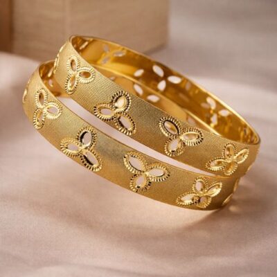 Exude a masterclass in texture and light with this pair of stunning gold-toned bangles. Combining a unique sand-blasted matte finish with intricate openwork floral motifs, these pieces offer a sophisticated, architectural take on traditional jewelry.