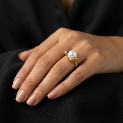 Embrace the peak of timeless luxury with this impeccably crafted gold-toned open ring. Featuring a masterclass in asymmetrical balance and soft, organic luster, this piece offers a sophisticated "bypass" silhouette that reimagines the classic pearl ring for the modern era.